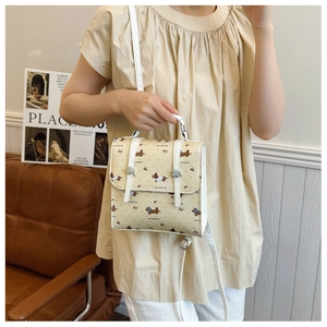 Detail of cream crossbody bag featuring cartoon dachshund patterns and white straps