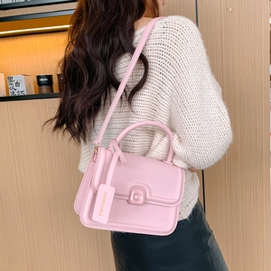 Pink matte leather crossbody bag with top handle and fashion tag shown on model