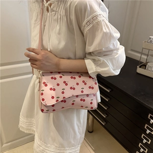 Pink crossbody bag with cherry print and scalloped lid design for cute summer style