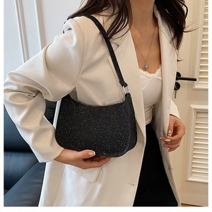 Model wearing a black glittery underarm bag with shimmering sequins and shoulder strap