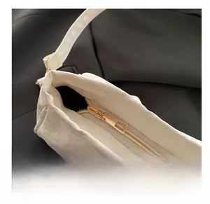 Detail of smooth gold zipper and white pleated leather texture on the shoulder bag