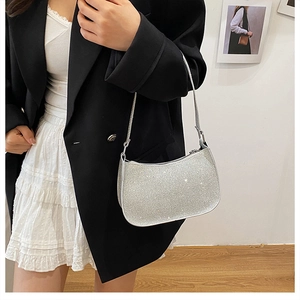 Détail d'un sac baguette argenté pailleté porté par un mannequin dans un décor épuré