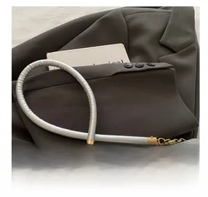 Detail of silver sequin bag featuring metallic cylindrical handle and gold metal clasp