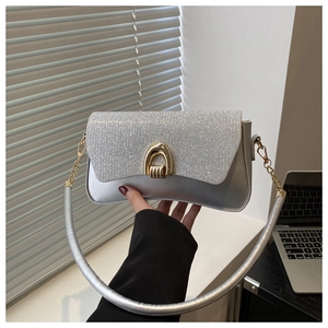 Detail of silver crossbody bag with sparkling rhinestones and gold horseshoe clasp
