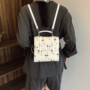 Mini cream backpack with cute dachshund prints and cherry details shown on a model back