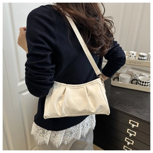 Model wearing a cream-white pleated underarm cloud bag with smooth leather texture