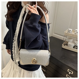 Detailed close-up of silver sequin square bag with golden chain strap and metallic buckle