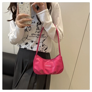 Detail of rose red pleated cloud bag featuring an oval fashion label on PU leather surface