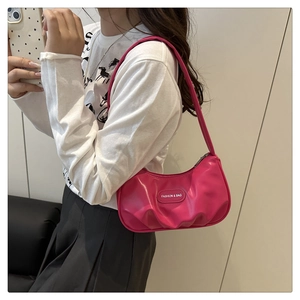 Detail of rose red pleated cloud bag worn as a shoulder bag on a model