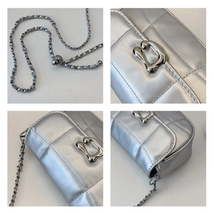 Detail view of silver quilted crossbody bag with metal chain strap and unique hardware clasp