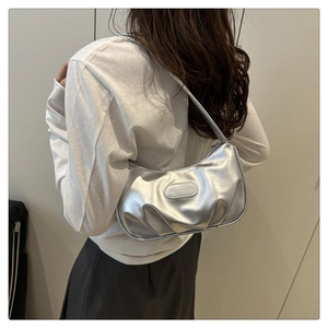 Close-up of silver crescent underarm bag with pleated PU leather and metallic logo