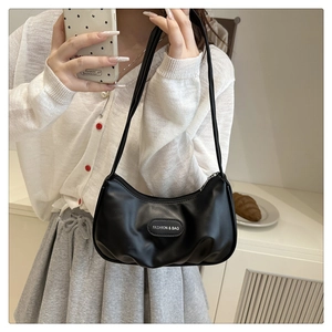 Detailed view of black pleated crescent bag with fashion metal logo and shoulder strap