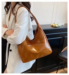 Detail of large caramel hobo bag showing glossy finish and side pocket on model