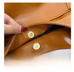 Detail showing the magnetic snap closure and caramel faux leather texture of the bag