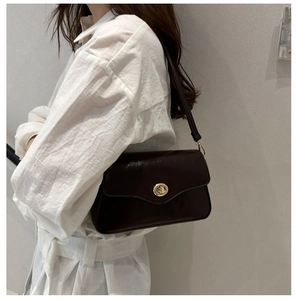 Detail shot of a dark brown faux leather shoulder bag with a gold metal twist lock