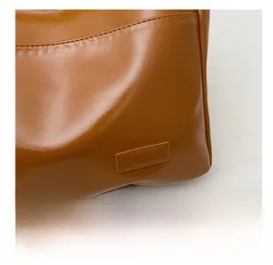 Close-up of brown leather bucket bag showing fine stitching and side pocket details