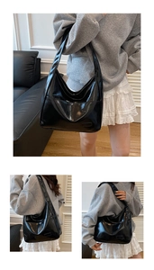 Detail view of large black glossy tote bag with wide shoulder strap and soft leather texture