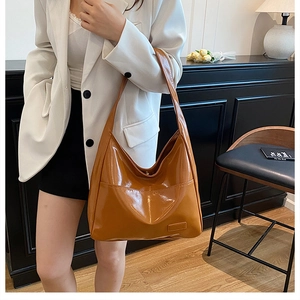 Dettaglio della borsa a secchiello in vernice lucida color caramello con blazer