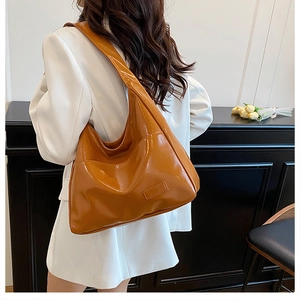Detailed back view of a glossy caramel brown oversized hobo shoulder bag worn by model