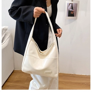 Dettaglio borsa tote in vernice crema con etichetta rettangolare e chiusura magnetica
