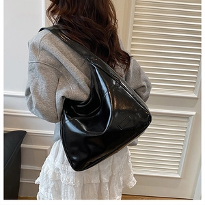 Dettaglio della borsa hobo in pelle verniciata nera lucida indossata da una modella