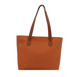Large orange-brown woven tote bag with dark brown leather handles on white background