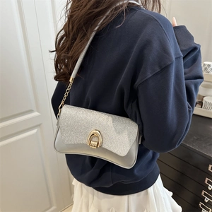 Chic silver sequin shoulder bag with golden horseshoe lock shown on a model