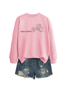 Dettaglio della felpa rosa con scritta 'thank a farmer' e pantaloncini in denim strappati