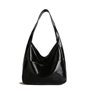 Minimalist large black tote bag with glossy finish and long shoulder strap on white background