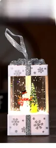 Close-up of Christmas gift box lantern with snowman and reindeer scenery inside