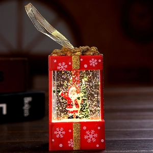 Lighted Christmas gift box snow globe with Santa and tree inside on wooden table