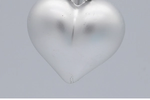 Detailed close-up of a silver heart-shaped Christmas ornament with a matte metal finish