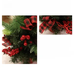 Detail of faux pine needles with red berries and a plaid bow on a mini Christmas tree