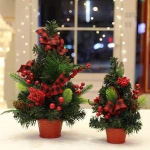 Mini tabletop Christmas trees with red bows and pine cones on a warm festive background