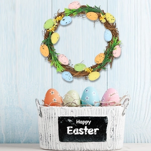 Easter wreath with colorful foam eggs and a Happy Easter basket on a light blue wood surface