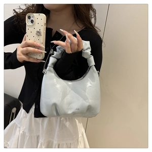 Close-up of light blue pleated dumpling bag with silver fashion text detail