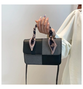 Close-up of the elegant scarf-wrapped handle on a contrast-stitched square bag