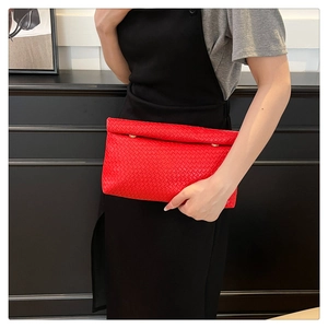 Close-up of woven red leather clutch bag featuring signature interlaced texture and gold hardware