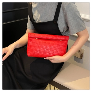 Detail of red woven leather clutch bag with metallic button closure and textured pattern