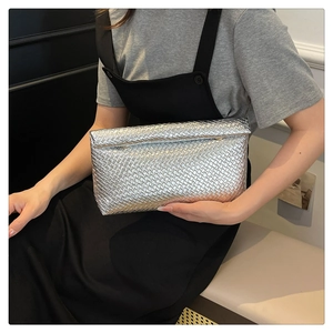 Detail of silver woven envelope clutch showing metallic texture and modern folding design