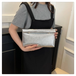 Close-up of silver woven texture clutch bag with metallic finish and envelope design
