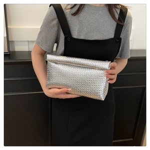 Detail of silver woven clutch bag featuring intricate Intrecciato pattern for urban style
