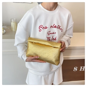 Close-up of golden woven envelope clutch bag with intricate metallic texture for women