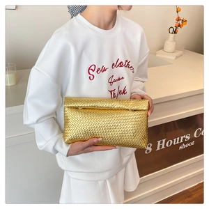 Detail of gold woven clutch showing intricate Intrecciato texture and metallic finish