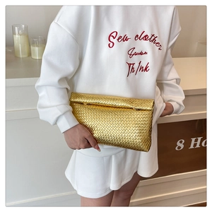 Close-up of woven metallic gold texture on a luxury envelope clutch bag