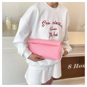 Detail shot of the pink woven texture and leather craftsmanship on the envelope clutch bag