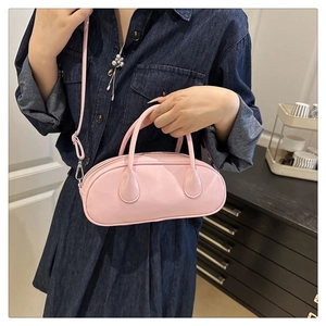 Close-up of light pink leather baguette bag with dual handles and long shoulder strap