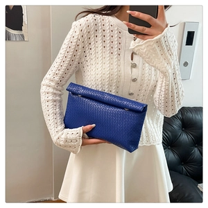 Detail of royal blue woven clutch bag featuring leather texture and gold ring buckle