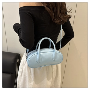 Blue glossy baguette bag worn over the shoulder by a model for size perspective