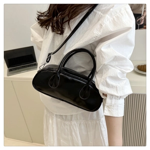 Detail of glossy black patent leather baguette bag with top handles and shoulder strap